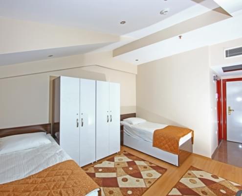 iki-kisilik-orenci-yurdu-odasi iki kişilik kız öğrenci yurdu odasının pencere tarafından çekilen geniş açılı fotoğrafı. sol karşıda iki yata ve eşya dolapları, sağda bir kısmı görünen buzdolabı ve sağ karşıda giriş kapısı