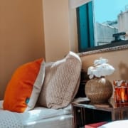 Nuvola Kız Öğrenci Yurdu, kaliteli donatısı ile öğrencilerine maksimum konfor sunuyor. Odalarımızda nitelikli uyku ürünleri, konforlu yataklar bulunuyor. Bu görselde, iki kişilik odaldaki yatalar ve arasındaki komodin yer alıyor. Yatakların hemen arkasında stor perde ile yarısı kapatılmış pencere bulunuyor.